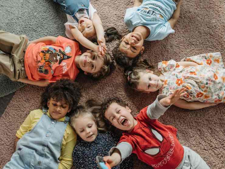 bambini distesi a terra in cerchio che ridono