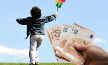 sfondo con bambino che corre nel prato con girandola e mano con banconote euro