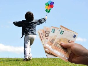 sfondo con bambino che corre nel prato con girandola e mano con banconote euro