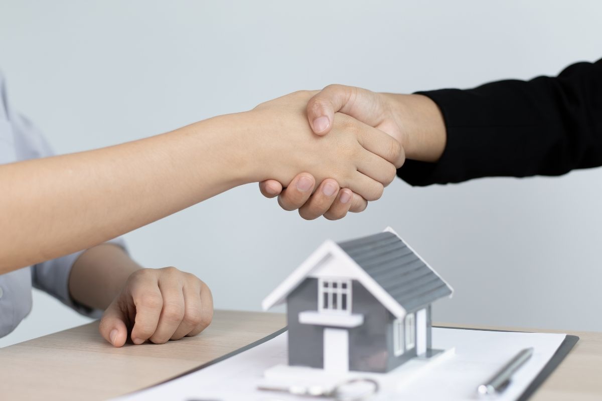 Stretta di mano e casa in miniatura