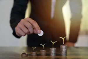 Persone con in mano una moneta e file di monete con piantine sopra