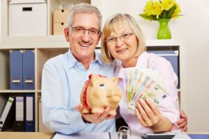 Pensionati felici che hanno in mano banconote e salvadanaio