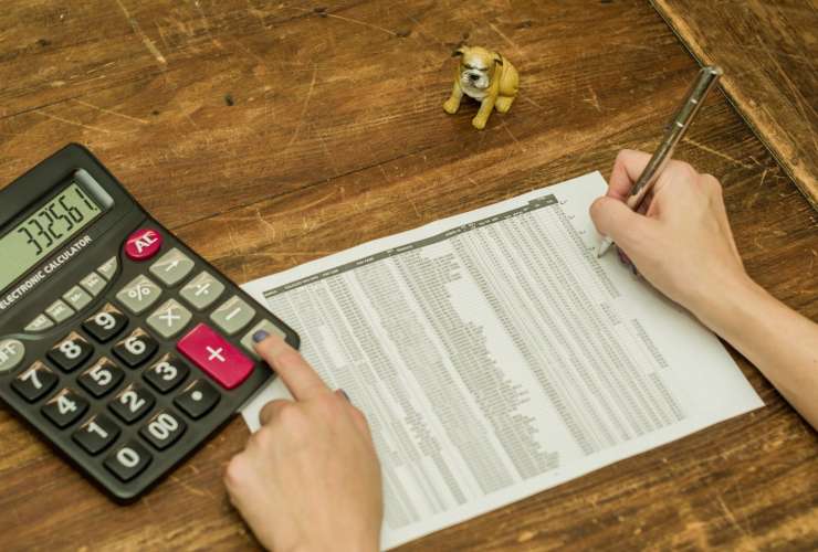 Calcolatrice e persona che prende appunti per i suoi investimenti