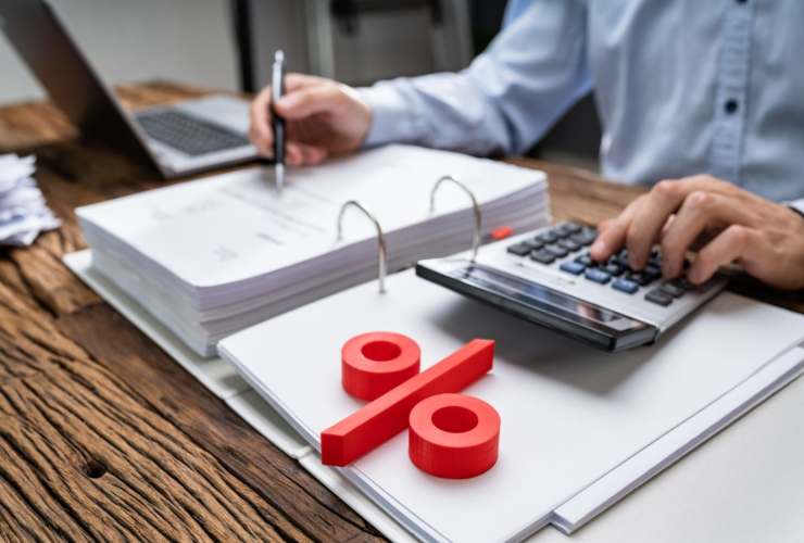 Persona che controlla documentazione fiscale e fa dei calcoli e simbolo percentuale