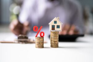 monete, simobolo pecentuale e miniatura casa